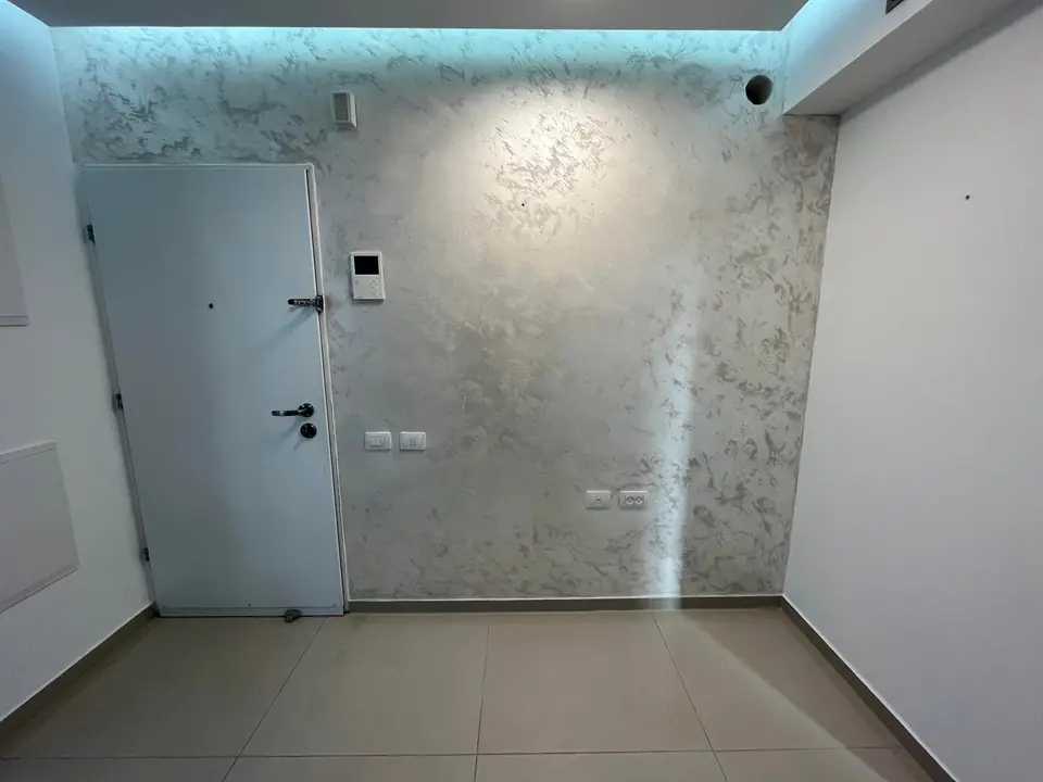 מבואה עם קיר בגימור דקורטיבי ותאורה נסתרת בתקרה